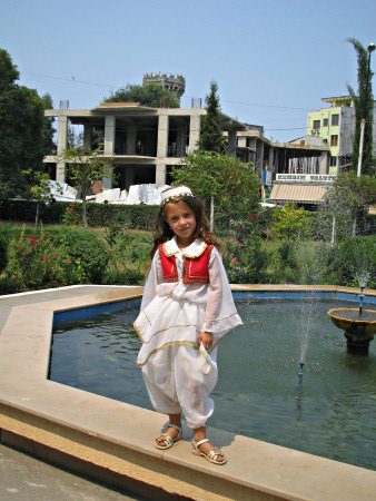 A young child is wearing a traditional white cloth with a red waistcoat.
