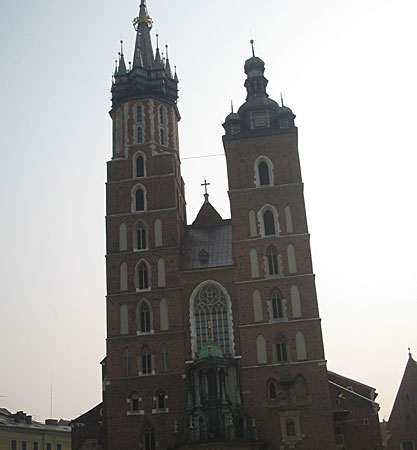 The facade of highbrick church with two asymmetric bell towers.