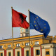 Albanian and European Union's flag wave next to each other in front of a large calssical building