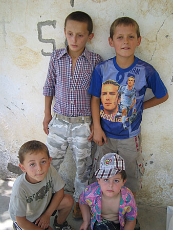 Four kids posing for a picture in front of a wall. One of them is wearing a Beckham t-shirt. 