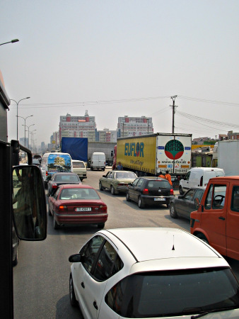 Cars and trucks queue in a five lanes road.