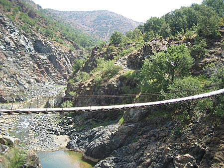 A rope and wood bridge crosses a rocky valley.