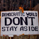 "Democratic world don't stay aside" written on a poster.