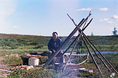 A young man sits next to a open air hearth