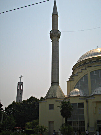 A bell tower of a church and a minaret and mosque, located not very far one from the other.