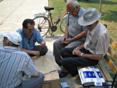 Four men sit around a box and play domino.